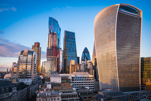 The iconic curves of The Gherkin framed by the illuminated office buildings of the City of London’s Square Mile Financial District, UK.