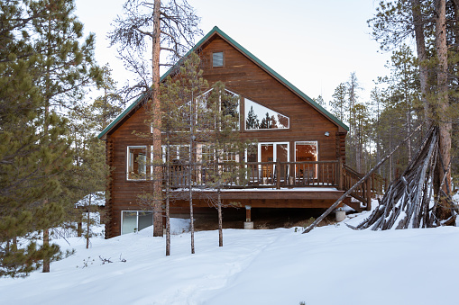 Exterior of log cabin in a snowy forest. Colorado in the winter. Vacation rental.