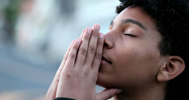 Young boy praying to God. Religious Mixed race child looking at sky with HOPE and FAITH stock photo