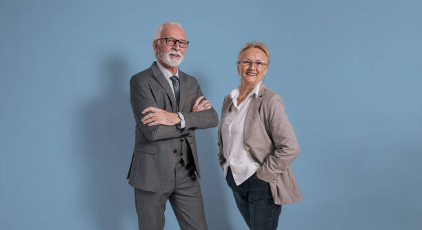 senior business professionals posing on blue background - 60 69 jaar fotos stockfoto's en -beelden