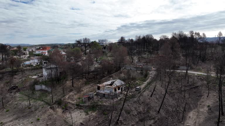 Aerial view orbiting crumbled residential property destruction after woodland wildfire natural disaster