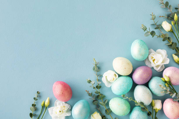 istock Easter greeting card with pastel easter eggs decorated flowers and green eucalyptus on blue table top view. 1469220562