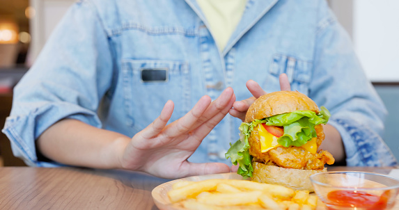 close up healthy eating diet concept - asian woman refuse unhealthy junk food hamburger and fries combo push them away