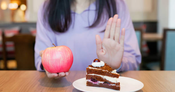 healthy eating choice close up healthy eating diet concept - asian woman hand hold apple choose eat apple refuse unhealthy dessert comb over stock pictures, royalty-free photos & images