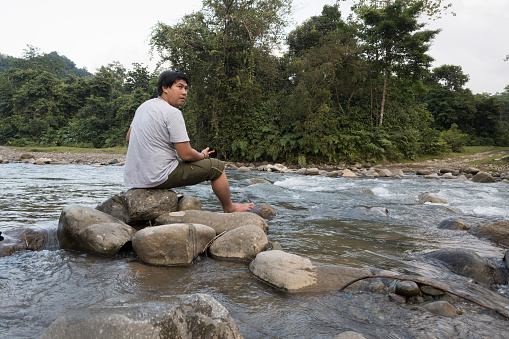 Men relaxing while enjoying coffee and playing cellphones in the river in the afternoon