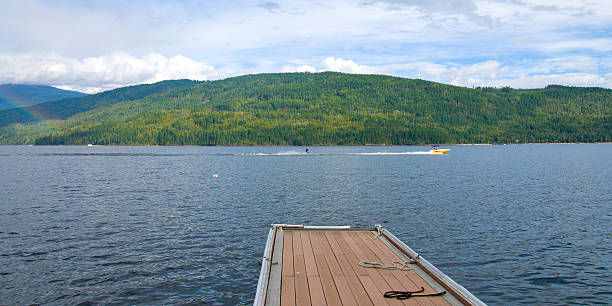 Pier on a mountain lake with people water sking in the background