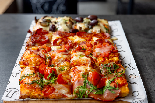 Pizza al taglio on a tray in restaurant, rectangular slices with various toppings served next to each other on a tray