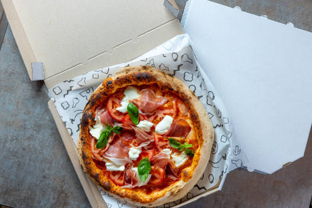 istock Pizza with prosciutto, tomato and mozzarella topping in open box for delivery 1469230966