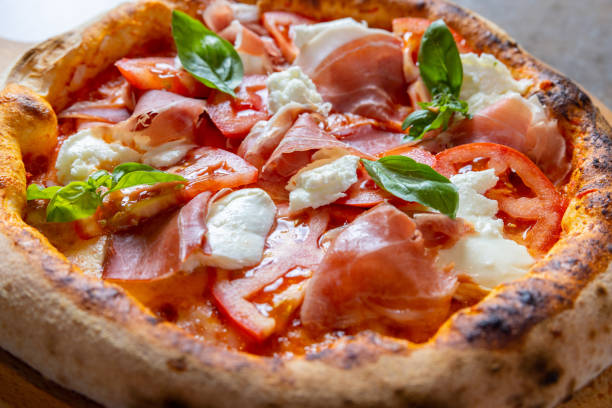 istock Close-up on round pizza with prosciutto, mozzarella and basil leaves on top 1469230977