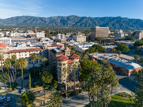 Aerial view of Pasadena, California with park, palm trees, historic hotel, city hall and mountains.