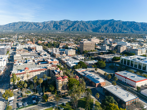 Aerial view of Pasadena, California with palm trees, historic hotel, city hall and mountains.