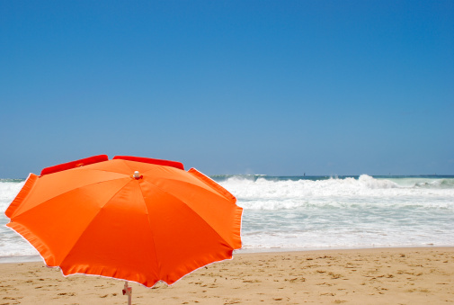 An orange sunshade under a blue sky at the beach