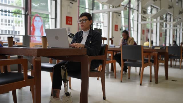 Transgender disabled woman using the laptop in the library