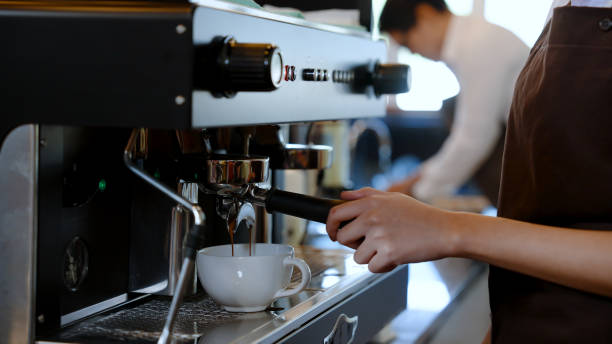 istock Barista water white coffee mug is a mug for hot coffee, put under coffee machine which is distilling coffee water, flows through handle coffee maker, Into a coffee mug ready to serve. 1469234325