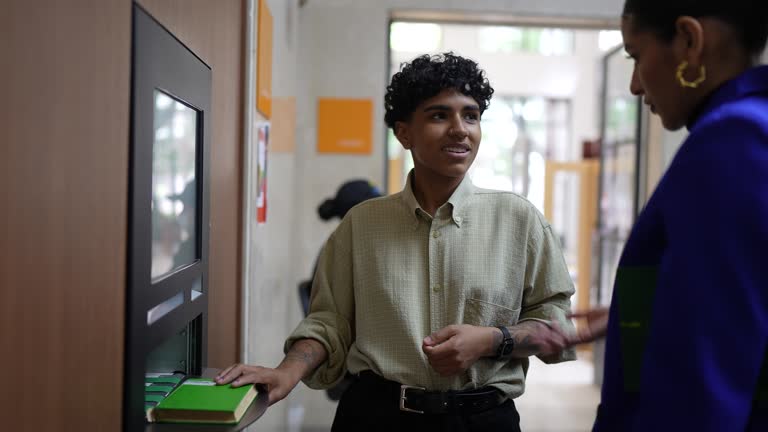 Young woman using the self checkout to borrow books from the library