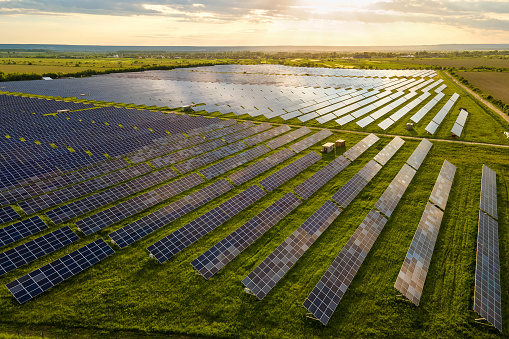 Aerial view of large sustainable electrical power plant with many rows of solar photovoltaic panels for clean ecological electric energy at sunrise. Renewable electricity with zero emission concept.