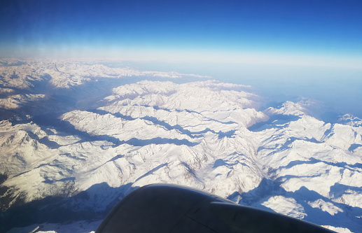 A beautiful view of the snow-capped peaks of the Alps from the window of a passenger plane.