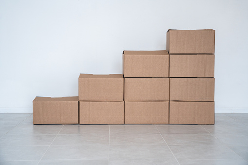 Cardboard boxes in empty interior, stacked as a chart or staircase, creative photography