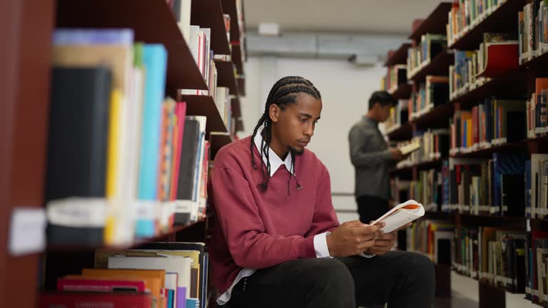 Young man reading a book in the library