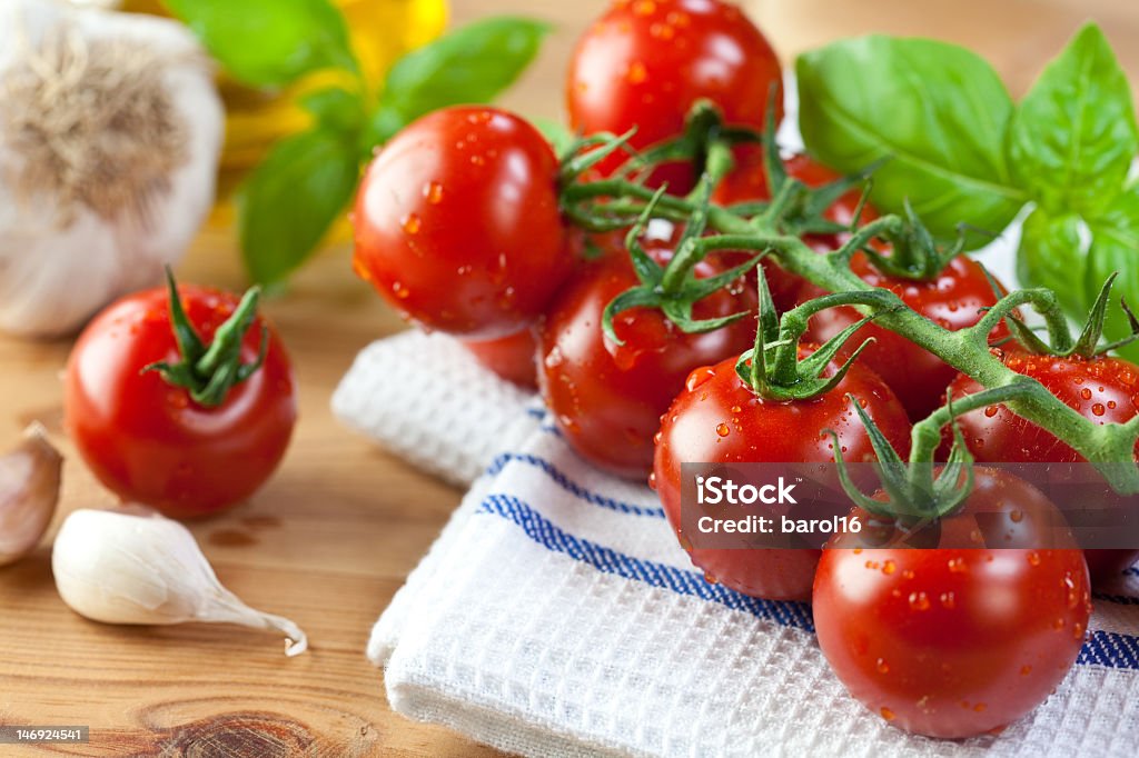 Fresh cherry tomatoes and basil on kitchen towel cherry tomatoes,basil and garlic on rustic kitchen table Basil Stock Photo