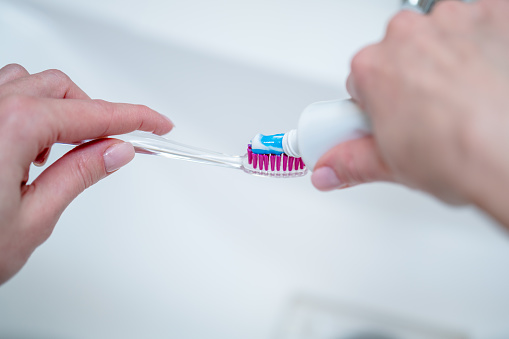 Close-up of toothbrush and a tube of toothpaste in a woman's hands
