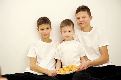 Two mixed race siblings are smiling and eating ice cream cones together. One of the boys has ice cream all over his face.