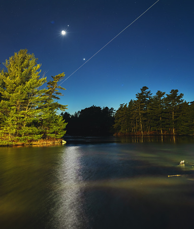 The Moon, Jupiter & Venus form an alignment in the evening skies above a still lake.