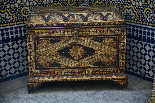 Vintage oriental metal studded wooden chest trunk, on a tile floor, used as a wardrobe in a Moroccan house in tanger, Morocco
