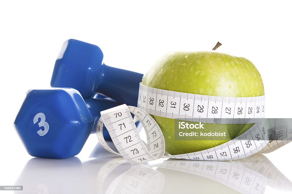 Dumbbells with green apple and measuring tape on white dumbbells and tape wrapped around apple - weight loss concept Blue Stock Photo