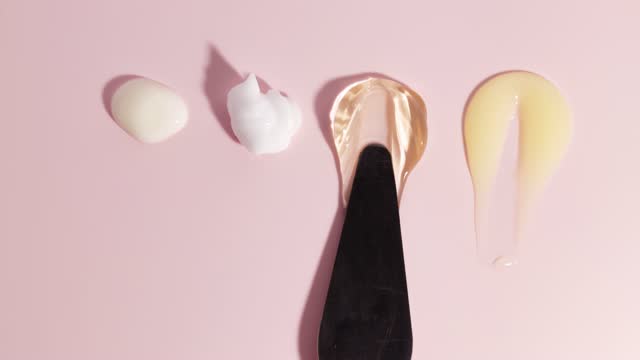 Composition of various cosmetic gel, mask, cream and serum smear on a pink background. Beauty texture. Sample of a cosmetic product. Stop motion animation.