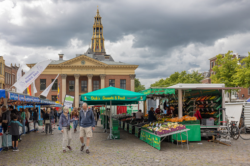 Groningen, The Netherlands - July 15, 2022: Shopping people near market stands at Vismarkt square near AA-kerk downtown medieval city Groningen