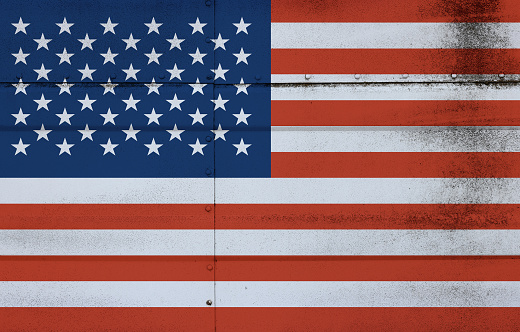 Grunge weathered national flag of USA over studded steel armor metal surface background, symbol of American patriotism
