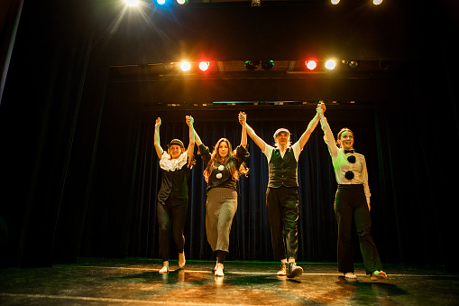 Four actors on stage taking the applause