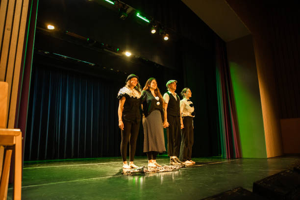 Four actors on stage taking the applause Four actors on stage taking the applause curtain call stock pictures, royalty-free photos & images