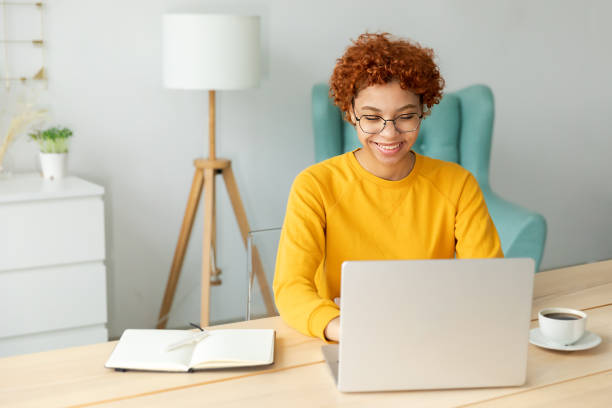 istock African american girl using laptop at home office looking at screen typing chatting reading writing email. Young woman having virtual meeting online chat video call conference Work learning from home 1469280399