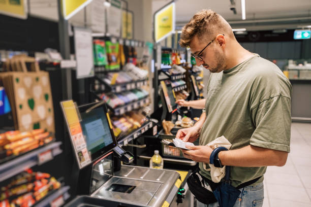 homme achetant et payant de l’argent au supermarché. photo avec les gens dans le magasin pendant les achats. la personne utilise le paiement sans contact - libre service photos et images de collection