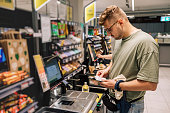 Man buying and paying money in the supermarket. Photo with people in the store during the shopping. Person is using contactless payment