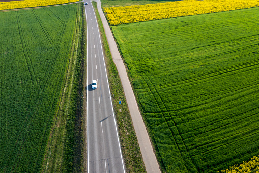 A white car on the road in spring landscape, aerial view.