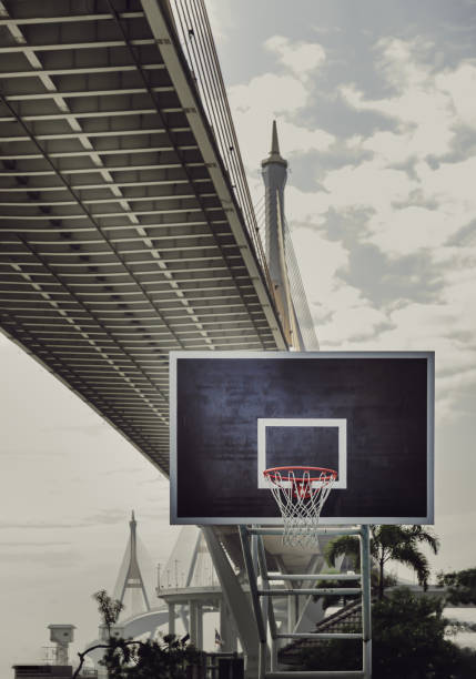 バスケットボールの木製バックボード、フープオレンジの金属リング、吊り橋に対する白いネットの眺め。 - concrete park city cityscape ストックフォトと画像