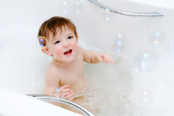 istock A happy child is playing with soap bubbles while sitting in a white home bathtub. Smiling toddler baby boy bathes in the bathroom. Kid aged one year six months 1469315669