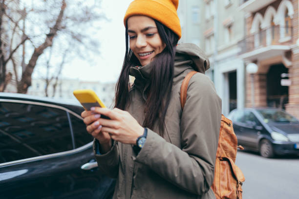 istock Woman with winter jacket and hat uses mobile phone 1469326036