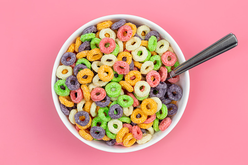 Colored breakfast cereal in a bowl on a pink background, flat lay, children's healthy breakfast, close up.