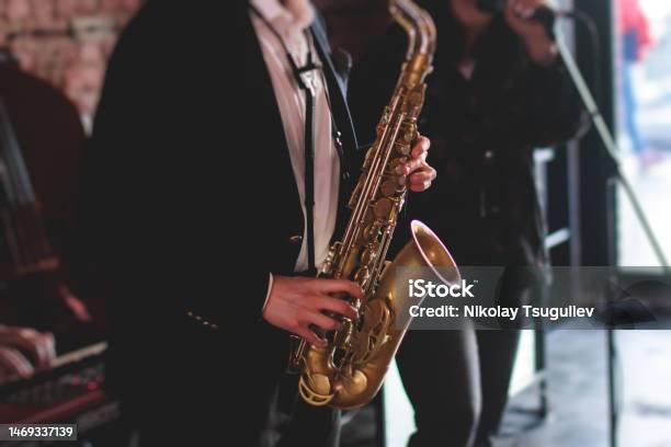 Concert View Of Saxophonist A Saxophone Sax Player With Vocalist And Musical Band During Jazz Orchestra Show Performing Music On A Stage In The Scene Lights Stock Photo - Download Image Now