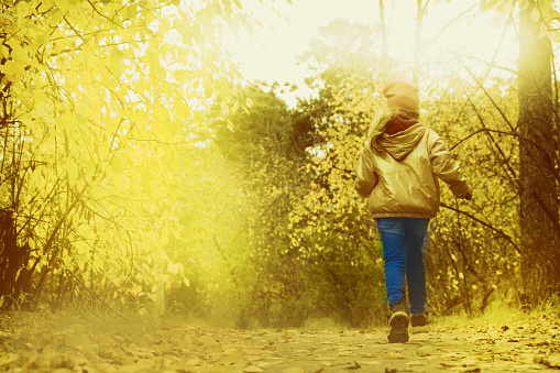 Little girl walking alone. Autumn park. Beautiful in nature. Cinematic effect toned