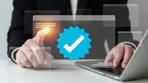 istock Businessman using laptop with verification account blue tick checkmark concept, verification account on social media platform, subscription status, eliminate bots, spam. 1469343774