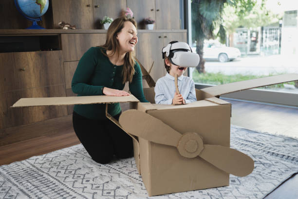 istock Mother and son having fun playing with virtual reality simulator in a plane from cardboard box 1469349901