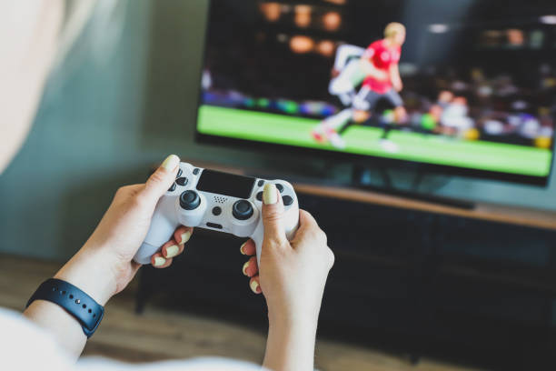 ビデオゲーム機で遊んでいる女の子。ゲームはサッカーです。ジョイスティックを手に。選択的焦点 - playstation ストックフォトと画像