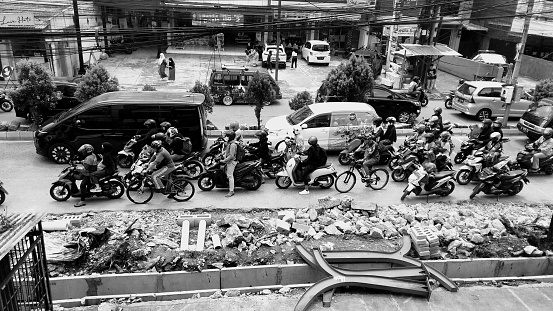 photo from above, the street is busy with cars and motorbikes, the roadside is being repaired. Photo location near Depok Station, West Java, Indonesia. November 5, 2022