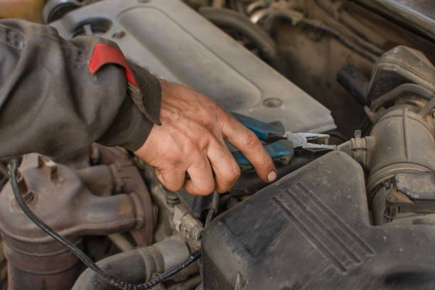 istock Mehanic repairs car engine, hand holds pliers 1469360368