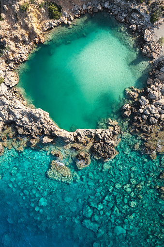 Small turquoise crater, surrounded by rocks, forming a small salt lake (Crete, Greece).